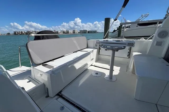 Slide: The Image of 2023 Beneteau Antares 8 boat deck with seating, table, and scenic waterfront view. - 9