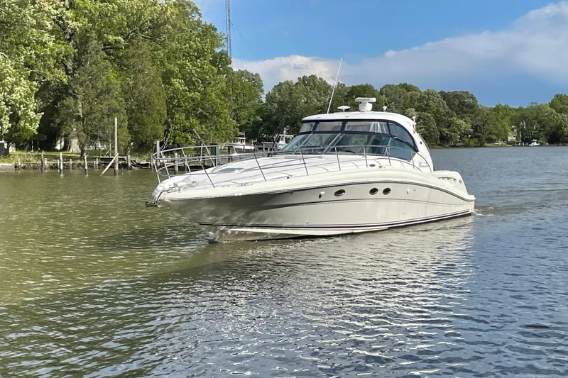 The Image of 2004 Sea Ray 420 Sundancer yacht cruising on a serene lake with lush greenery. - 0