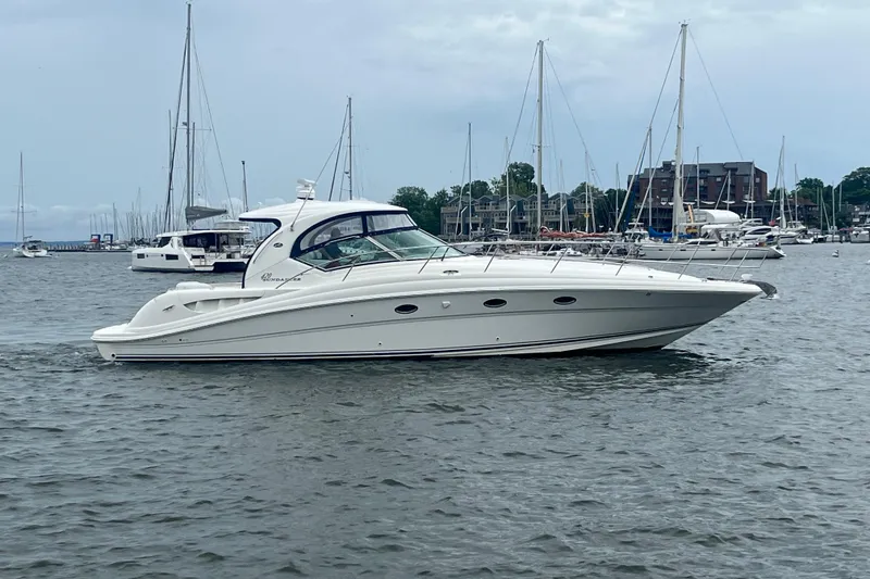 Slide: The Image of 2004 Sea Ray 420 Sundancer yacht cruising in a marina with sailboats in the background. - 3