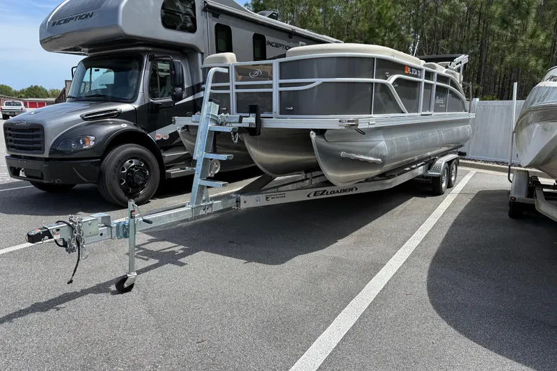 The Image of 2023 Barletta C22CC pontoon boat on trailer, parked beside RV. - 0