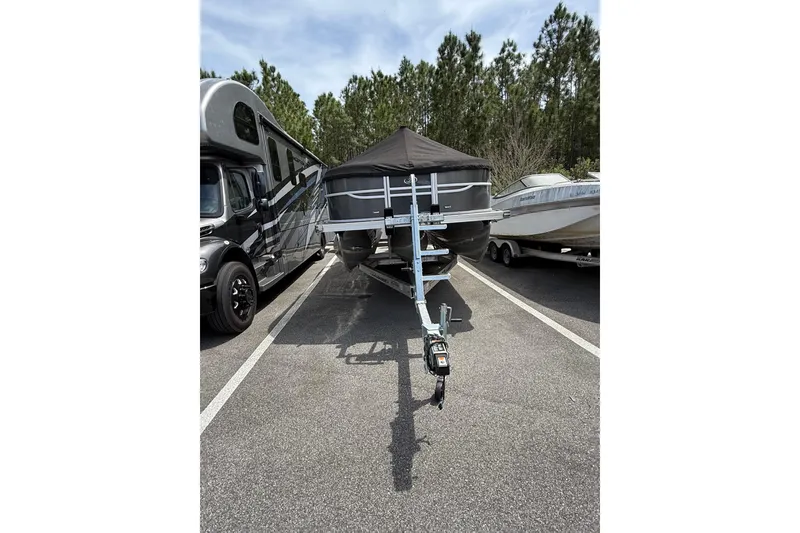 Slide: The Image of 2023 Barletta C22CC boat on trailer, parked between RV and another boat. - 10