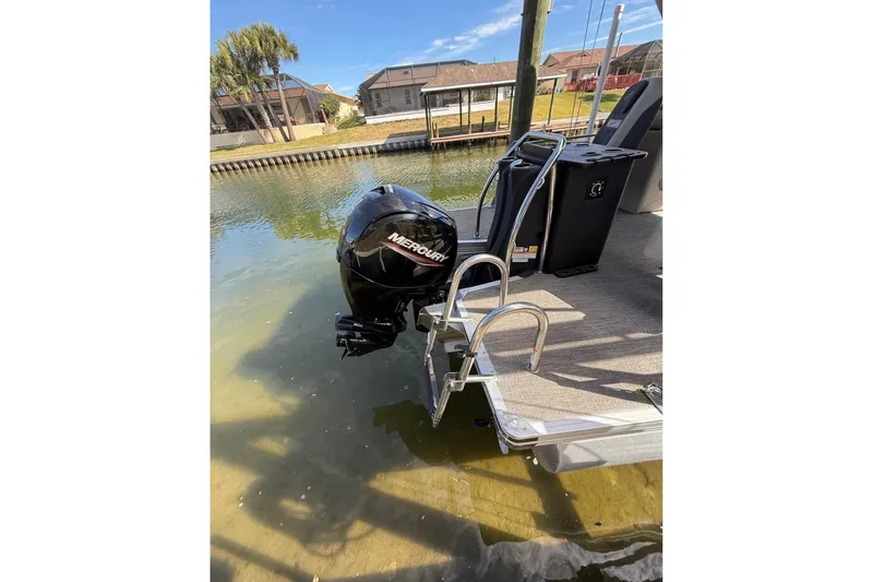 Slide: The Image of 2023 Barletta C22CC pontoon boat with Mercury outboard motor in a canal setting. - 3