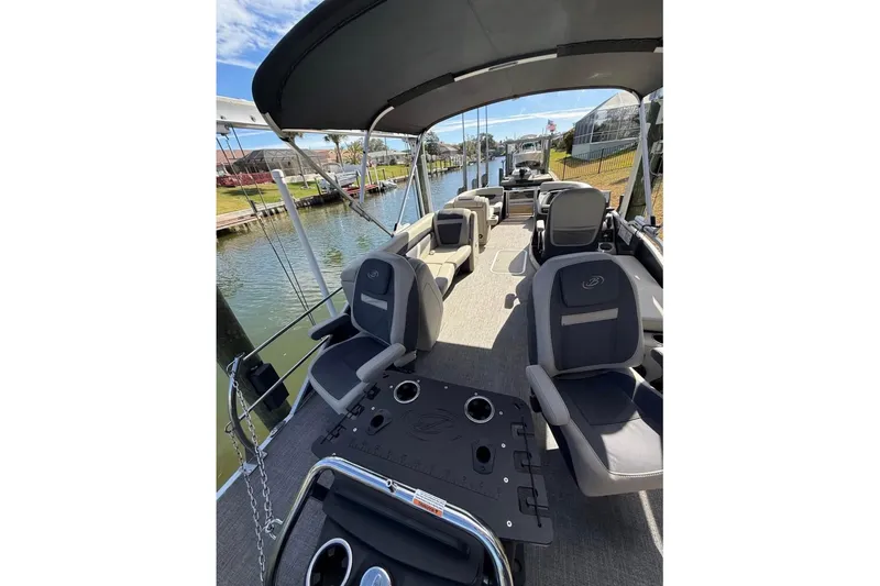 Slide: The Image of 2023 Barletta C22CC pontoon boat interior with seating and canopy on a sunny day. - 4