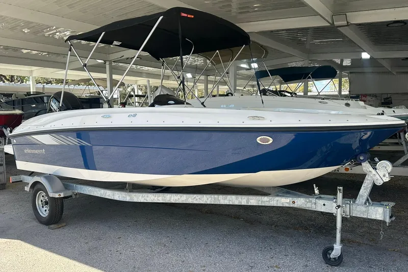 The Image of 2025 Bayliner Element E18 boat with canopy on trailer in covered storage. - 0