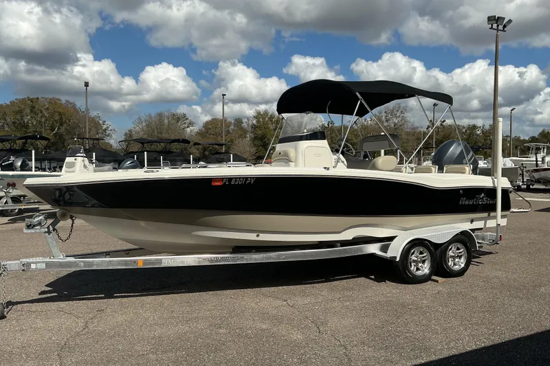 The Image of 2015 NauticStar 231 Hybrid boat on trailer under cloudy sky. - 0