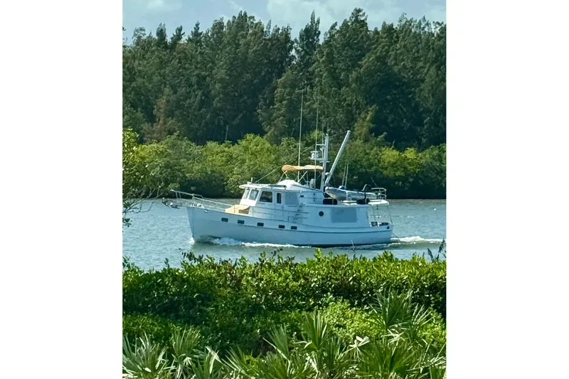 Slide: The Image of 2008 Kadey-Krogen 44 yacht cruising on calm waters with lush greenery. - 3