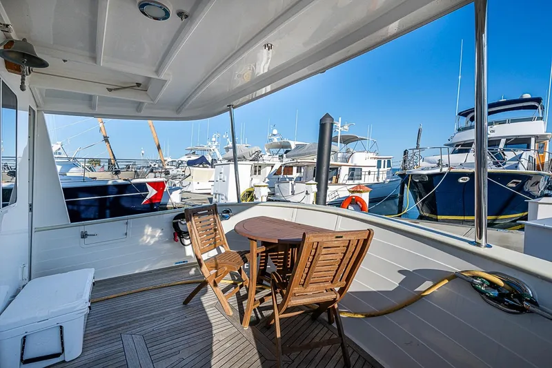 Slide: The Image of 2008 Kadey-Krogen 44 yacht deck with wooden chairs, marina view, and moored boats. - 47
