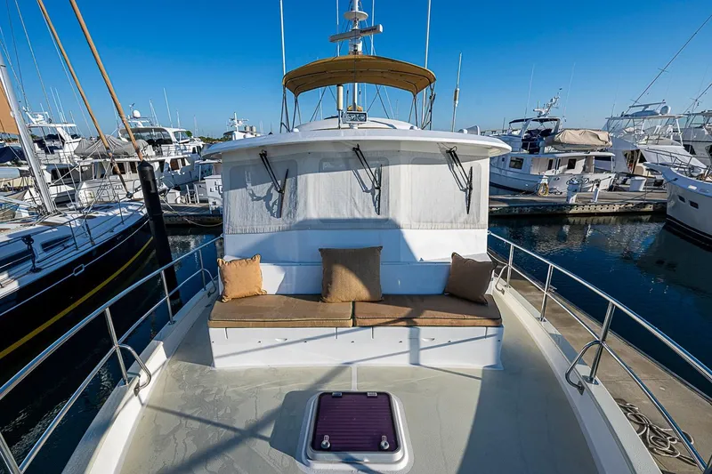 Slide: The Image of 2008 Kadey-Krogen 44 yacht with cushioned seating, docked in a marina under clear blue skies. - 49