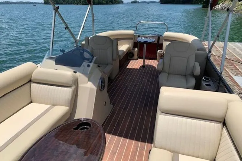 Slide: The Image of 2016 Crest 2360 SLC pontoon boat interior with beige seating on a lake. - 10