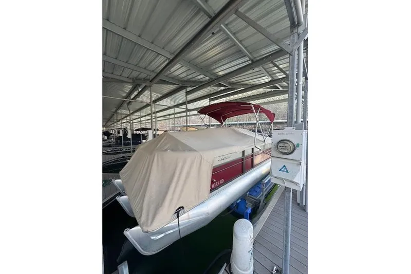 Slide: The Image of 2016 Crest 2360 SLC pontoon boat docked under a metal canopy. - 13