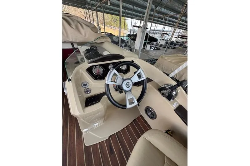Slide: The Image of 2016 Crest 2360 SLC boat dashboard with steering wheel and controls in a covered marina. - 8