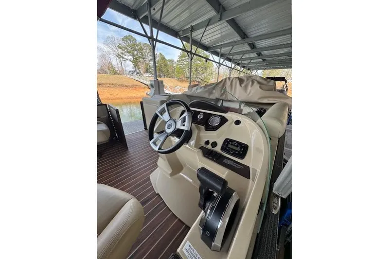 Slide: The Image of 2016 Crest 2360 SLC boat interior with steering wheel and controls under a covered dock. - 9