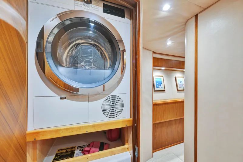 Slide: The Image of Laundry area inside 2011 Viking 70 Convertible yacht with wood paneling and framed artwork. - 18