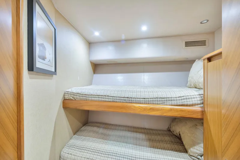 Slide: The Image of Bunk beds in 2011 Viking 70 Convertible yacht cabin, featuring cozy bedding and soft lighting. - 21