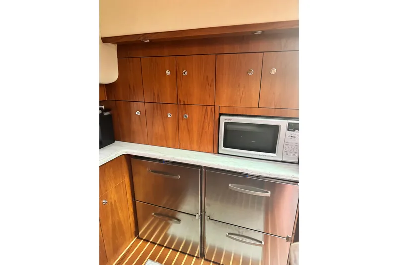 Slide: The Image of 2014 Tiara Yachts 4300 Open galley with wood cabinets, microwave, and stainless steel appliances. - 20