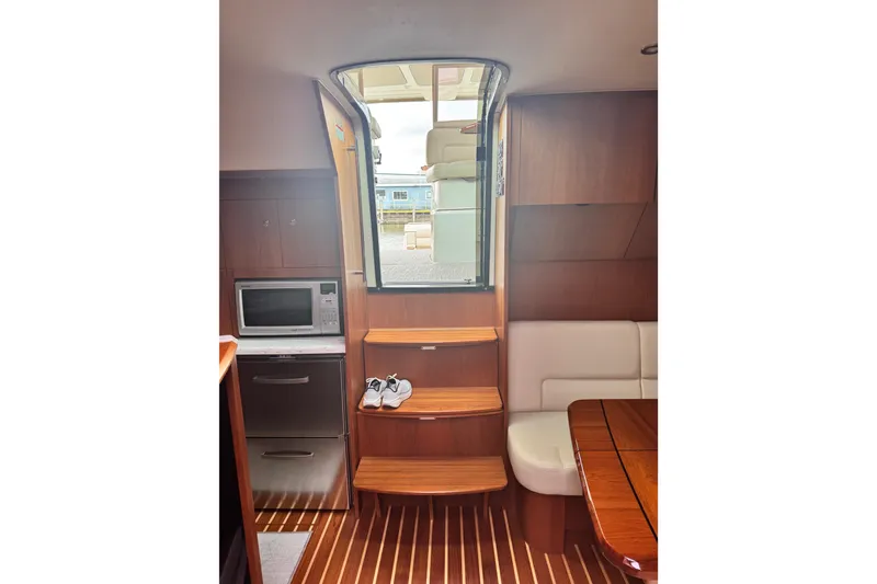Slide: The Image of Interior of 2014 Tiara Yachts 4300 Open, featuring wooden steps, microwave, and seating area. - 21