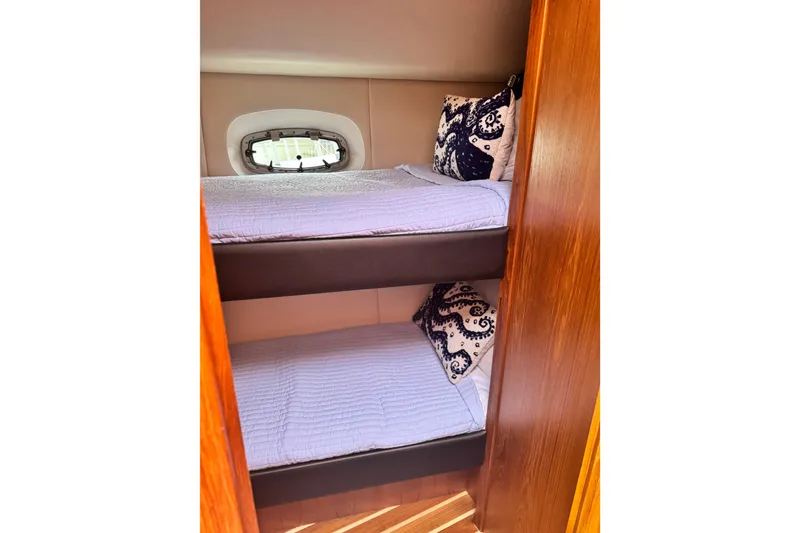 Slide: The Image of Bunk beds in 2014 Tiara Yachts 4300 Open, featuring cozy bedding and decorative pillows. - 23