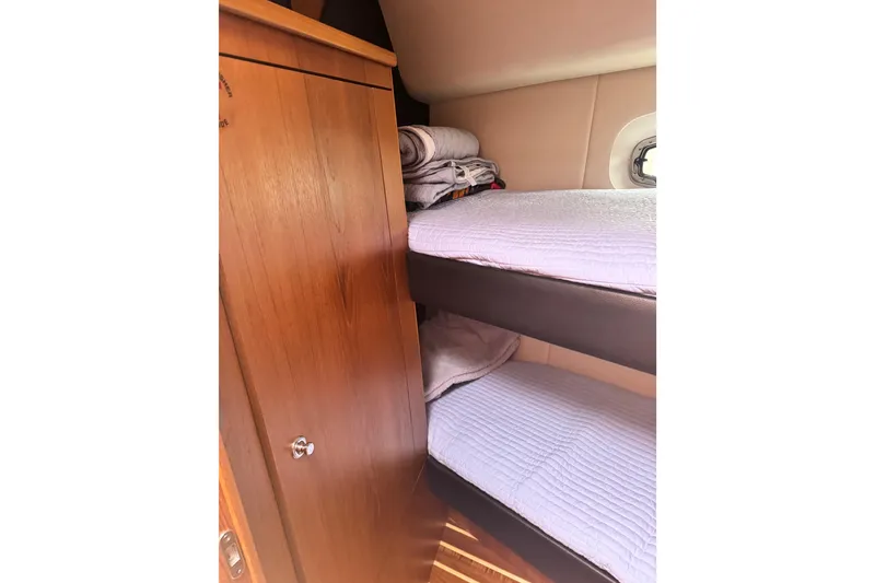 Slide: The Image of Bunk beds in 2014 Tiara Yachts 4300 Open cabin, featuring wooden cabinetry and porthole. - 24