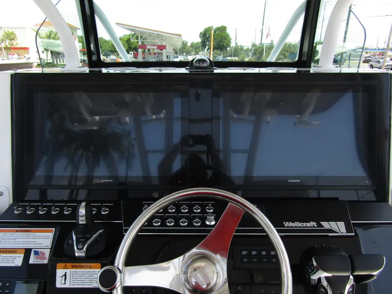 Slide: The Image of 2024 Wellcraft 352 Fisherman boat dashboard with dual Garmin displays and steering wheel. - 21