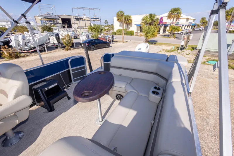 Slide: The Image of 2021 South Bay 222CR pontoon boat interior with seating and table, parked outdoors. - 14