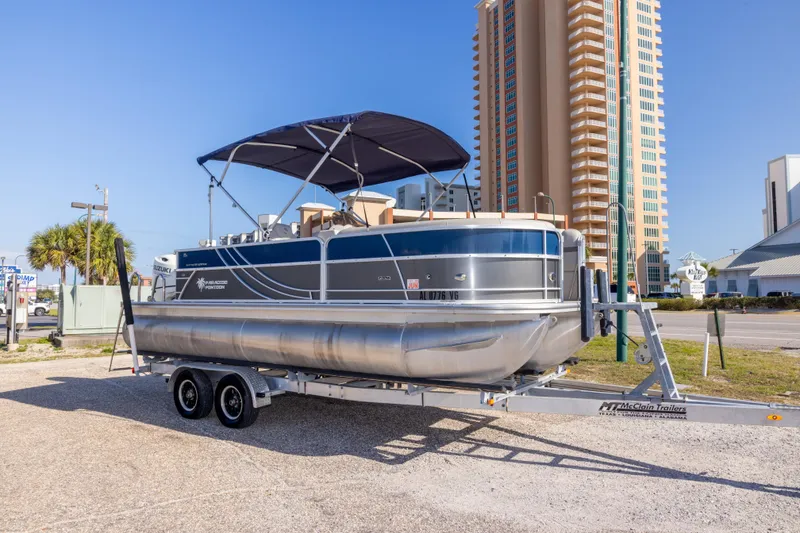 Slide: The Image of 2021 South Bay 222CR pontoon boat on trailer, parked near tall buildings. - 2