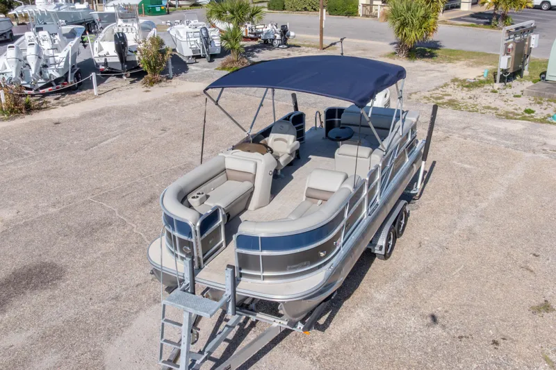 Slide: The Image of 2021 South Bay 222CR pontoon boat with canopy on trailer, parked in a lot. - 21