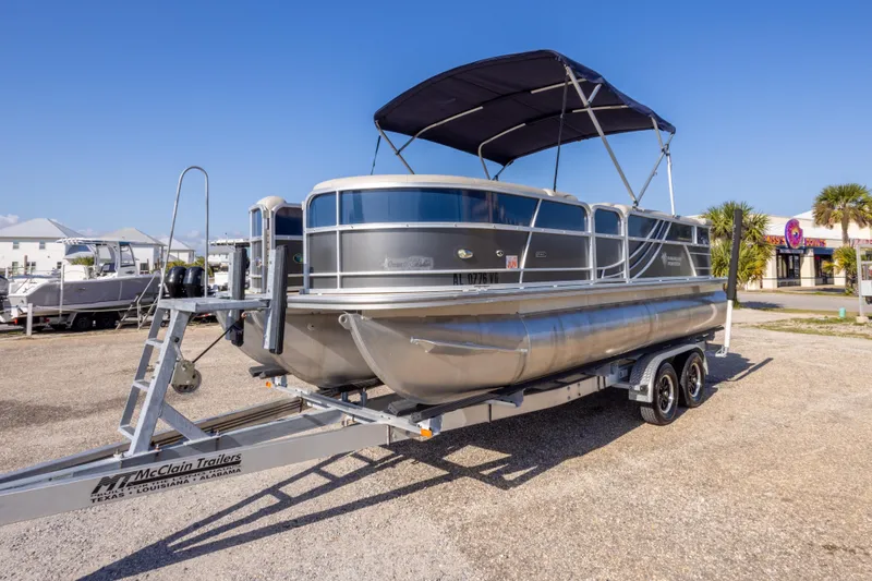 Slide: The Image of 2021 South Bay 222CR pontoon boat on trailer, parked outdoors under clear blue sky. - 7