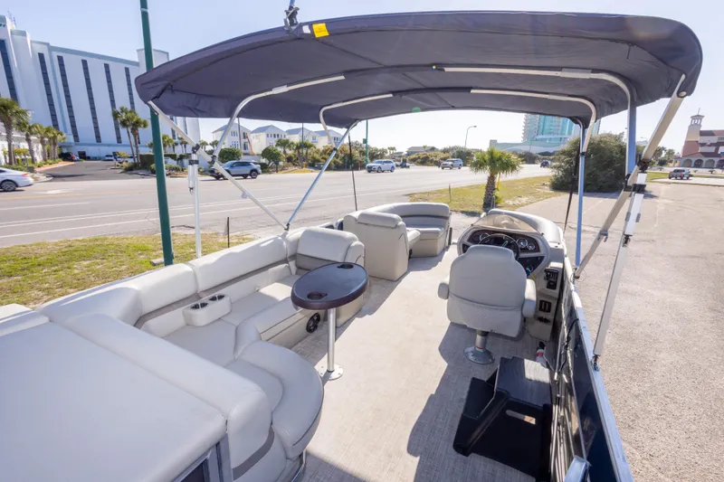 Slide: The Image of 2021 South Bay 222CR pontoon boat with spacious seating and canopy, parked near a road. - 9