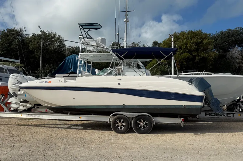 The Image of 2004 Hurricane SunDeck 260 OB boat on trailer, parked outdoors under cloudy sky. - 1