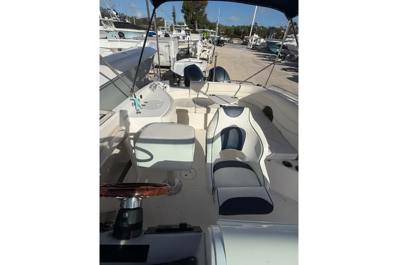 Slide: The Image of 2004 Hurricane SunDeck 260 OB boat interior with seating and steering wheel, docked among other boats. - 13