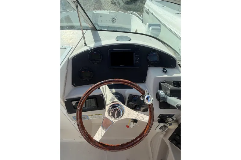 Slide: The Image of 2004 Hurricane SunDeck 260 OB boat dashboard with wooden steering wheel and control panel. - 18