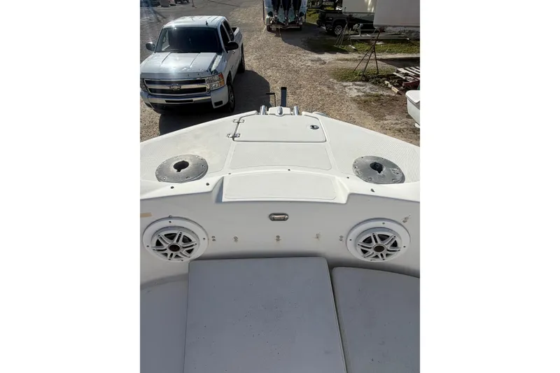 Slide: The Image of 2004 Hurricane SunDeck 260 OB boat deck with speakers, parked near a silver truck. - 23