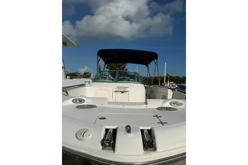 Slide: The Image of 2004 Hurricane SunDeck 260 OB boat with canopy under a clear blue sky. - 4