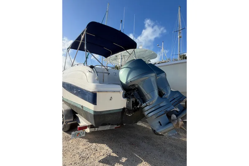 Slide: The Image of 2004 Hurricane SunDeck 260 OB boat with dual outboard motors and canopy, parked on trailer. - 7