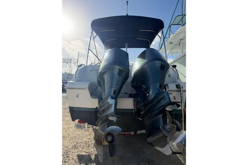 Slide: The Image of 2004 Hurricane SunDeck 260 OB with dual outboard motors, docked under sunny skies. - 8