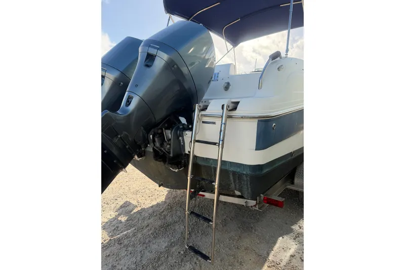 Slide: The Image of 2004 Hurricane SunDeck 260 OB boat with dual outboard motors and boarding ladder. - 9