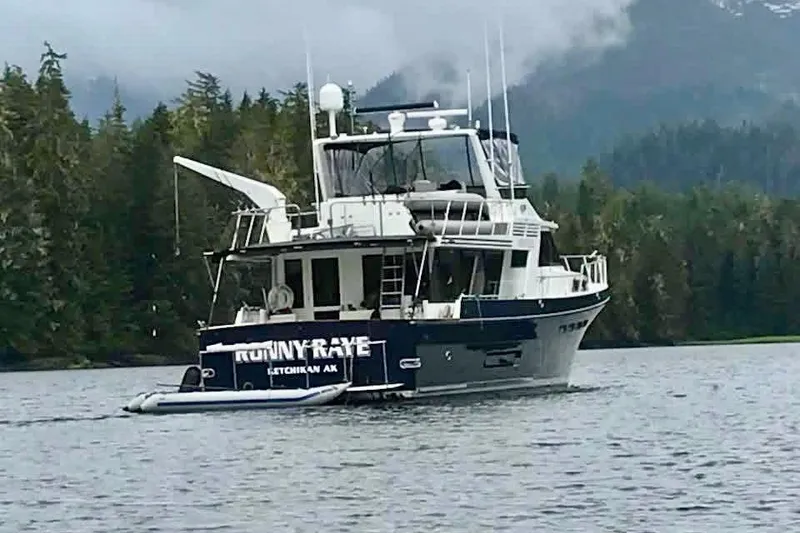 Slide: The Image of Nordlund 68 yacht from 1991 on a serene lake with forested backdrop. - 2