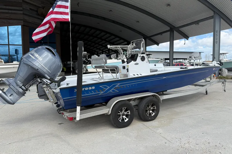 Slide: The Image of 2021 Xpress H24B Bay boat on trailer with Yamaha outboard motor and American flag. - 2