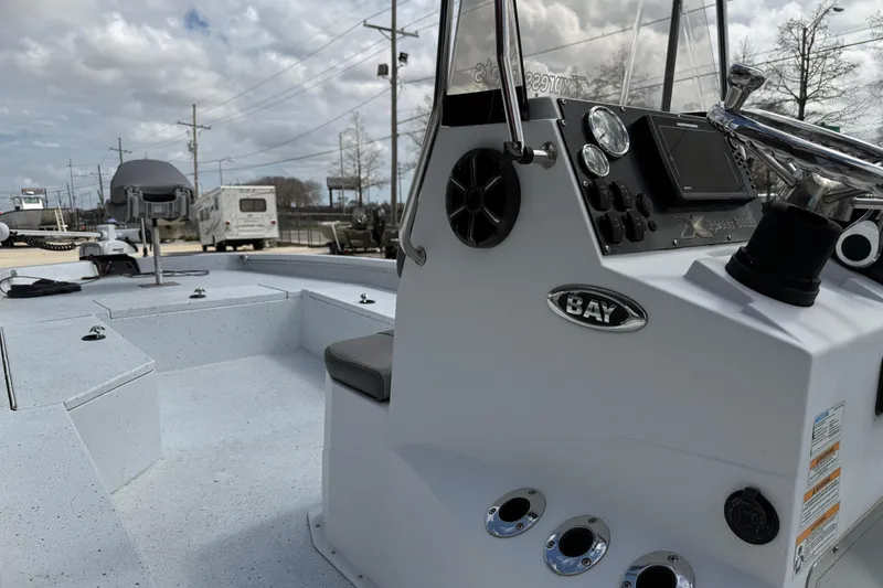 Slide: The Image of 2021 Xpress H24B Bay boat interior with steering console and seating, under cloudy sky. - 7