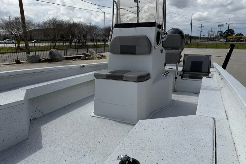 Slide: The Image of 2021 Xpress H24B Bay boat interior with seating and console, parked outdoors. - 9