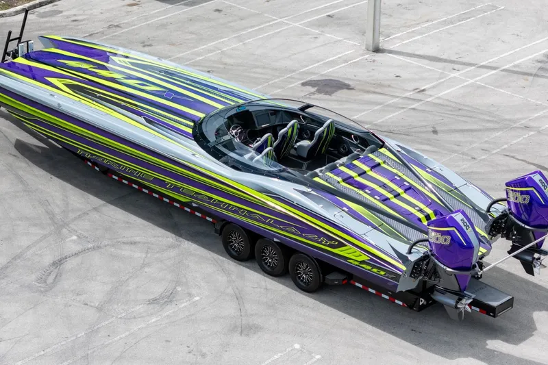 The Image of 2024 MTI 440X powerboat with vibrant purple and green design on a trailer. - 1