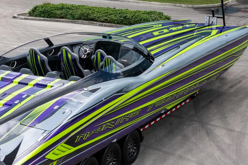 Slide: The Image of 2024 MTI 440X powerboat with vibrant green and purple design, parked on a trailer. - 16