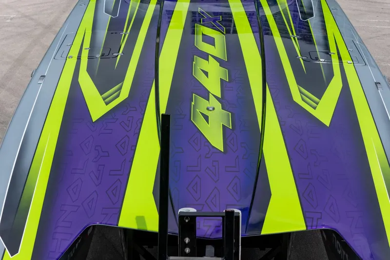 Slide: The Image of 2024 MTI 440X boat with vibrant green and purple graphics on deck. - 19