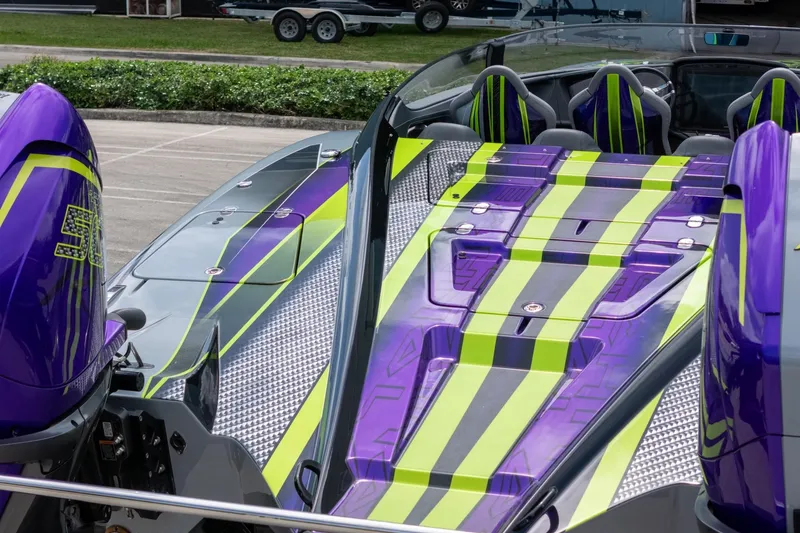 Slide: The Image of 2024 MTI 440X powerboat with vibrant purple and green design, parked outdoors. - 21