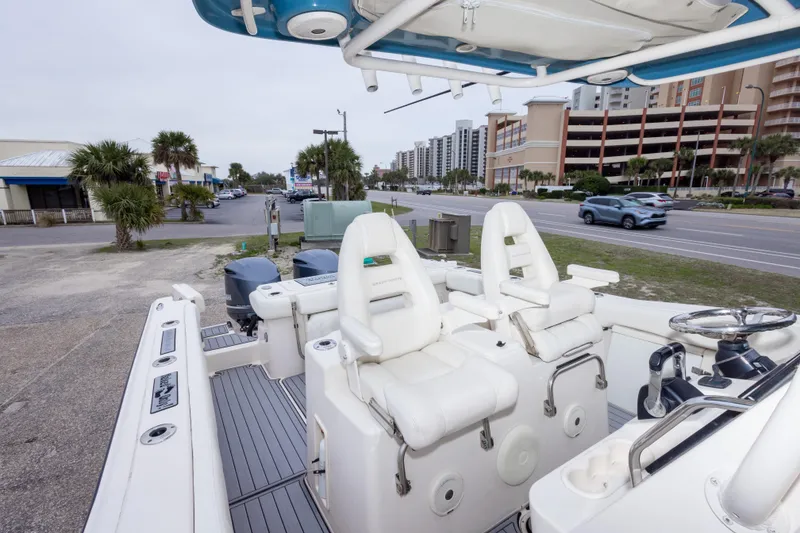 Slide: The Image of 2017 Grady-White Canyon 306 boat interior with white seating and steering wheel, parked near a road. - 35