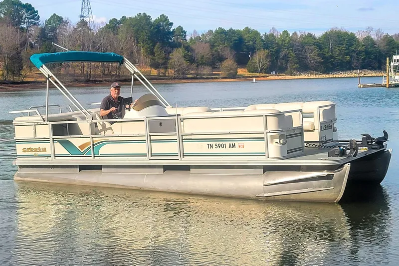 The Image of 2000 Crest 25' Pontoon boat on a lake with a person steering. - 1
