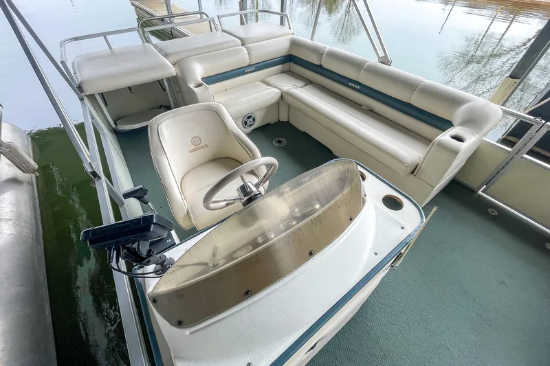 Slide: The Image of 2000 Crest 25' Pontoon boat interior with seating and steering console on calm water. - 14