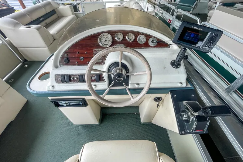 Slide: The Image of 2000 Crest 25' Pontoon boat dashboard with steering wheel and navigation system. - 17
