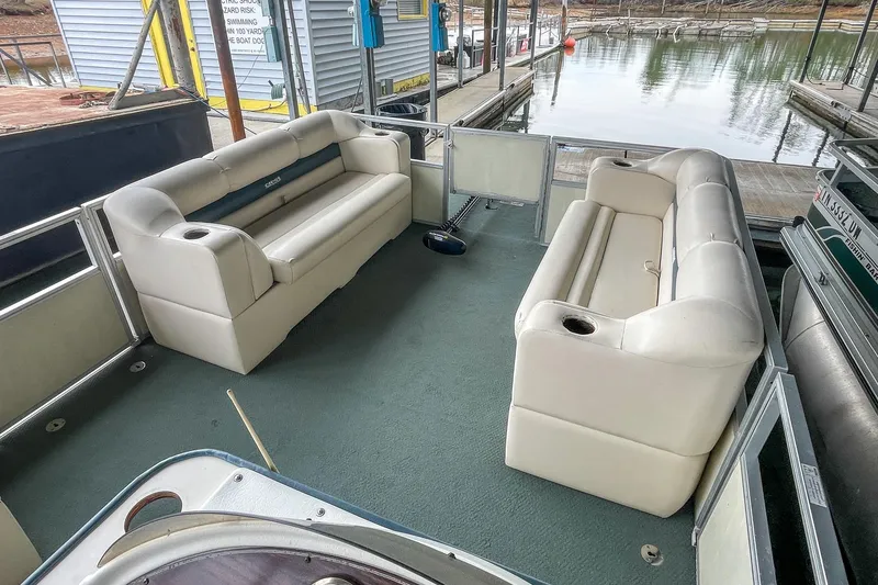 Slide: The Image of 2000 Crest 25' Pontoon boat interior with white seating and green carpet at a dock. - 18