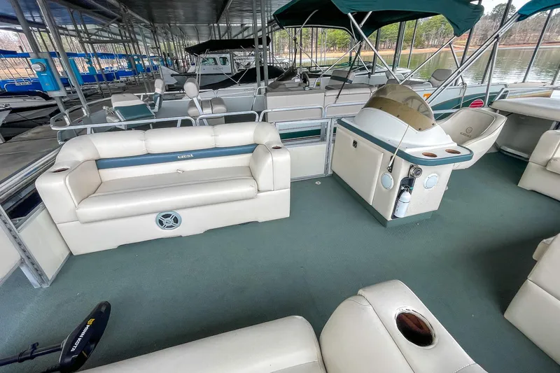 Slide: The Image of 2000 Crest 25' Pontoon boat interior with seating and helm, docked at marina. - 8